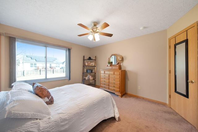 bedroom featuring light carpet, ceiling fan, a textured ceiling, and baseboards