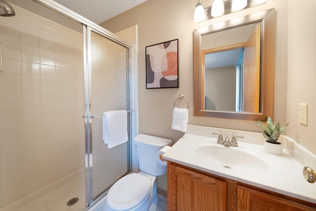 bathroom with a stall shower, toilet, vanity, and a textured ceiling