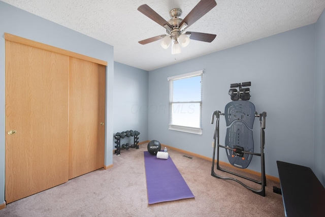 workout area featuring visible vents, baseboards, carpet flooring, a textured ceiling, and a ceiling fan