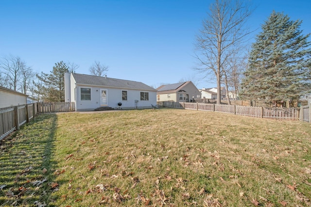 rear view of house featuring a lawn and a fenced backyard