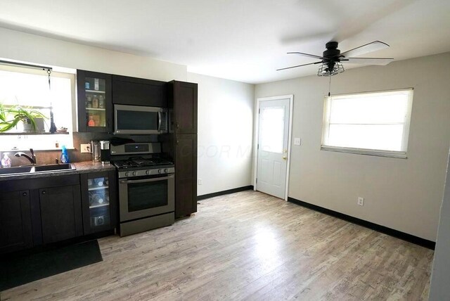 1664 Deporres Dr, Columbus, OH 43219 - kitchen featuring glass insert cabinets, baseboards, a sink, light wood-type flooring, and stainless steel appliances
