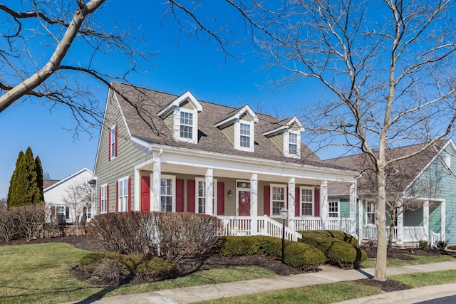 cape cod house with covered porch and a shingled roof