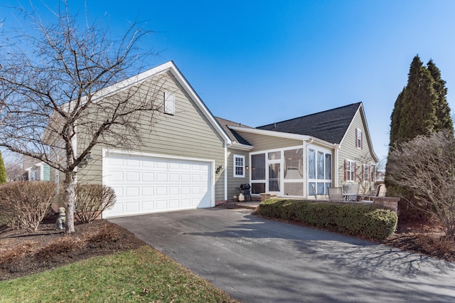 view of front of home featuring aphalt driveway, an attached garage, and a sunroom