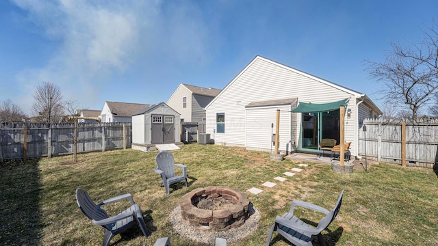 back of property featuring a lawn, an outdoor fire pit, a fenced backyard, and an outdoor structure