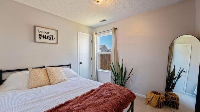 carpeted bedroom with visible vents, baseboards, and a textured ceiling