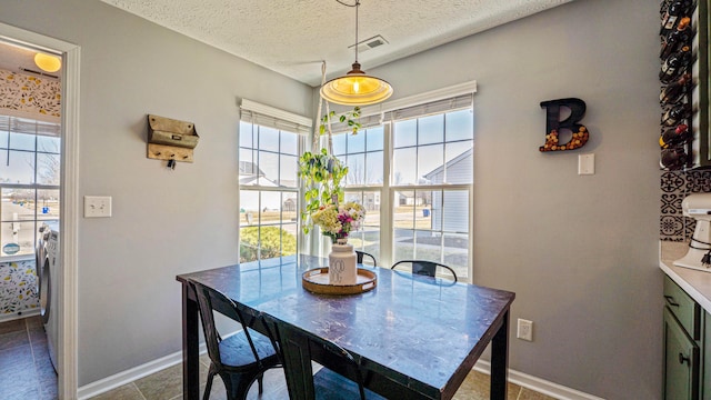 dining area featuring baseboards, visible vents, and a textured ceiling