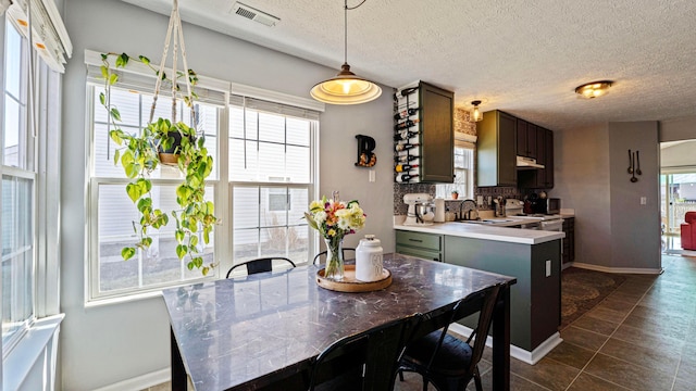 kitchen featuring visible vents, dark tile patterned flooring, a sink, light countertops, and tasteful backsplash