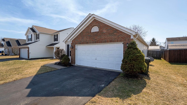 view of front facade with driveway, fence, a front yard, a garage, and brick siding