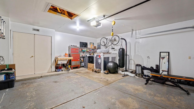 garage with a workshop area, a garage door opener, and visible vents