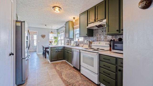 kitchen with under cabinet range hood, a peninsula, stainless steel appliances, and green cabinets