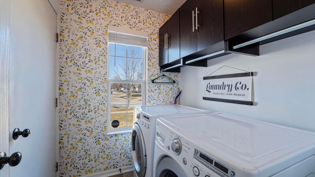 washroom featuring cabinet space, washing machine and dryer, wallpapered walls, and a textured ceiling