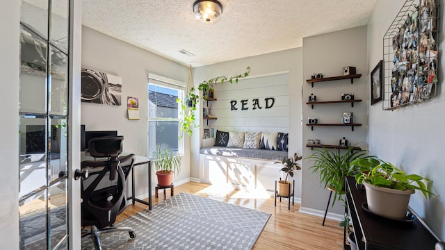 home office with visible vents, wood finished floors, baseboards, and a textured ceiling