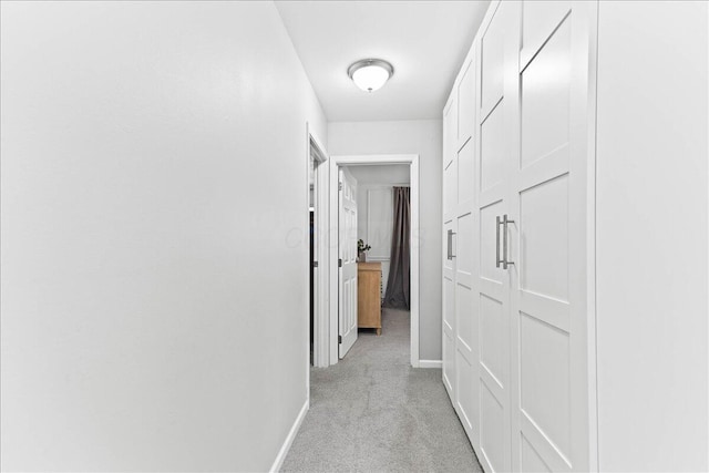 hall with baseboards and light carpet