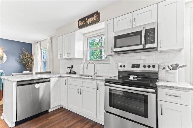 kitchen featuring dark wood-type flooring, stainless steel appliances, white cabinets, and a sink