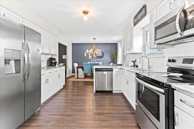 kitchen featuring a sink, a chandelier, tasteful backsplash, white cabinetry, and appliances with stainless steel finishes
