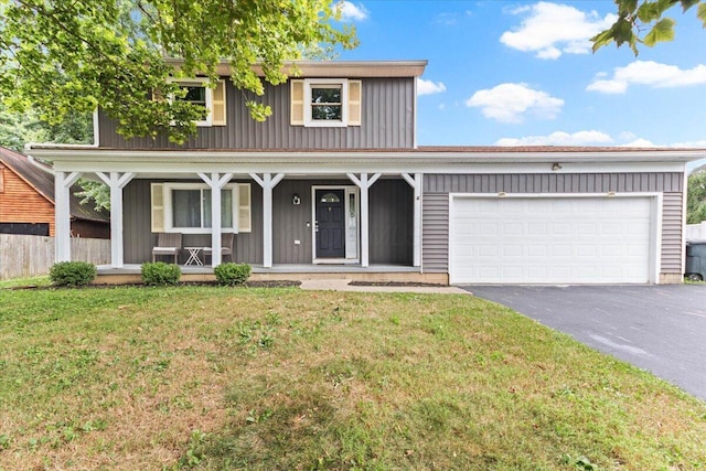 traditional-style home with driveway, covered porch, a front yard, and an attached garage