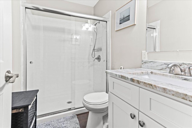 bathroom with a shower stall, toilet, and vanity