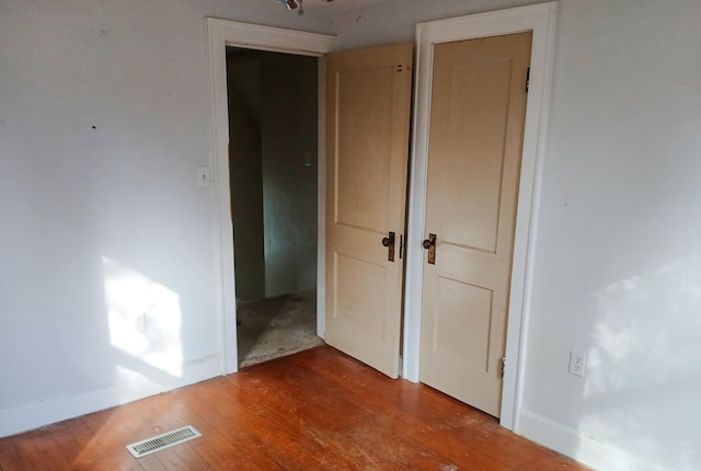 empty room featuring visible vents, baseboards, and wood finished floors