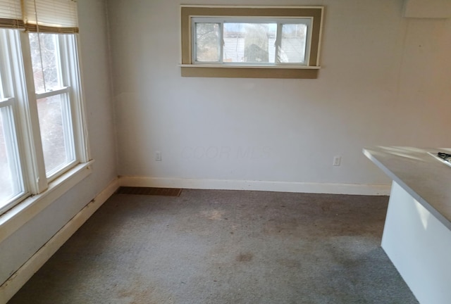 unfurnished room with baseboards and a wealth of natural light