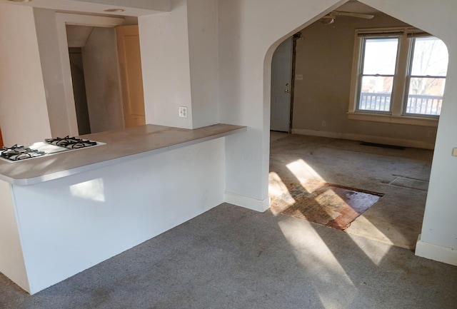 kitchen with cooktop, carpet, arched walkways, and a ceiling fan