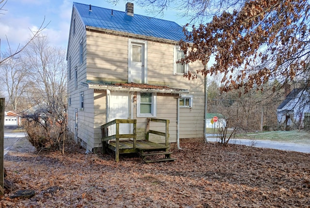 back of house with metal roof and a chimney