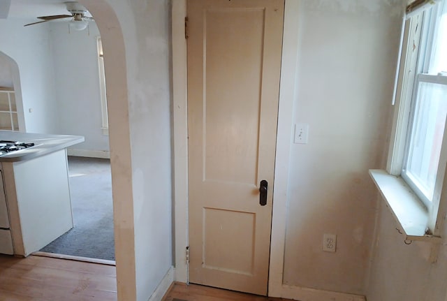 hallway featuring arched walkways and light wood finished floors