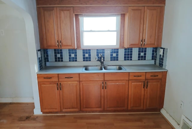 kitchen featuring a sink, decorative backsplash, brown cabinets, and visible vents