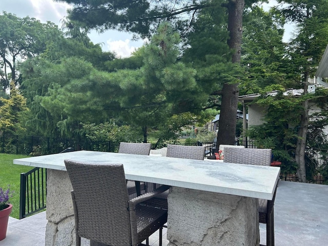 view of patio with outdoor dry bar and fence