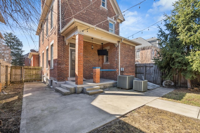 rear view of house featuring a fenced backyard, brick siding, and central AC