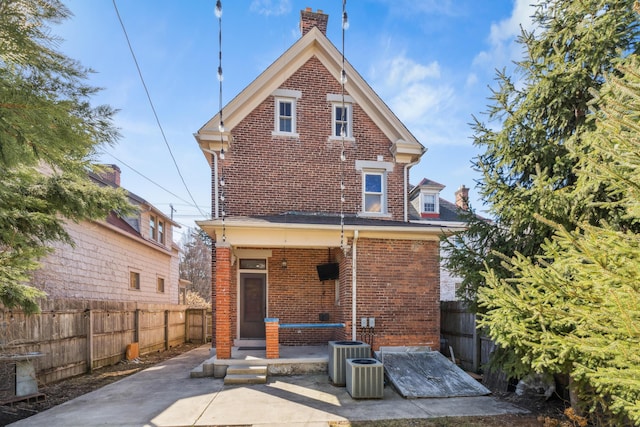 rear view of property with central AC unit, a porch, fence, and brick siding