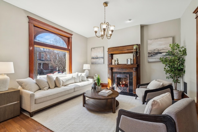 living area featuring visible vents, a notable chandelier, wood finished floors, and a high end fireplace