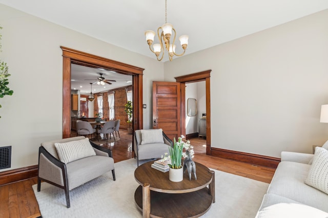 living room with light wood finished floors, a chandelier, and baseboards