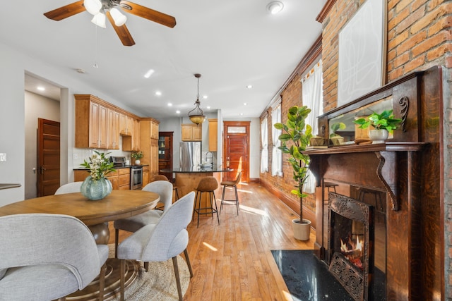 dining area with light wood-type flooring, a ceiling fan, a high end fireplace, recessed lighting, and baseboards