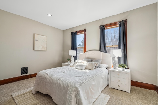 bedroom with visible vents, light colored carpet, and baseboards