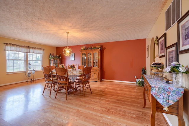 dining space featuring light wood-type flooring, baseboards, a textured ceiling, and visible vents