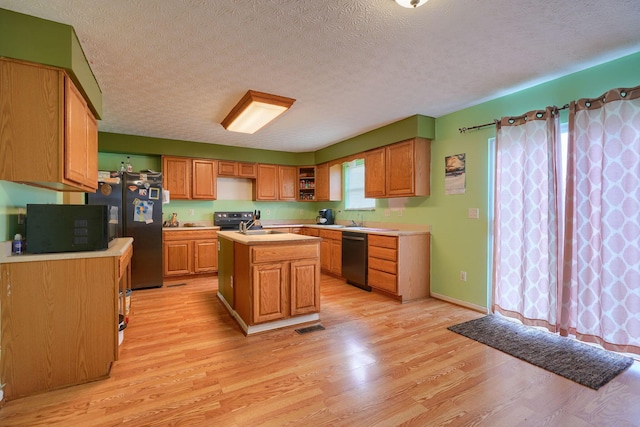 kitchen with dishwashing machine, light wood-style floors, light countertops, and a kitchen island