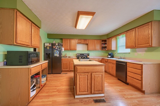 kitchen featuring a center island with sink, light countertops, light wood-style floors, stainless steel appliances, and open shelves