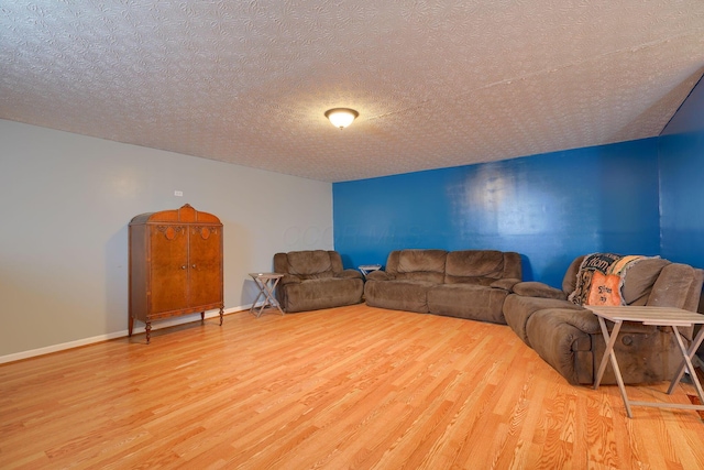 living area featuring baseboards, a textured ceiling, and wood finished floors