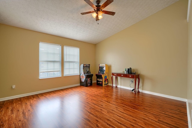 interior space featuring baseboards, a textured ceiling, ceiling fan, and wood finished floors