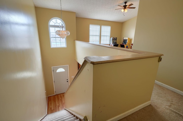 entryway featuring ceiling fan with notable chandelier, baseboards, and a textured ceiling