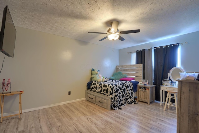 bedroom featuring baseboards, a textured ceiling, wood finished floors, and a ceiling fan