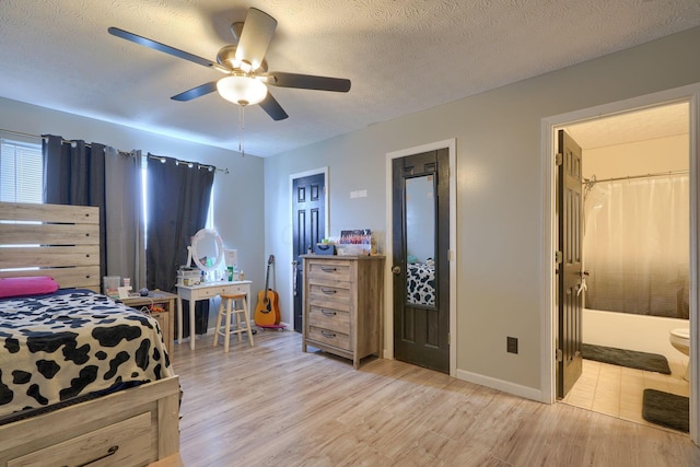 bedroom with baseboards, light wood finished floors, ceiling fan, a textured ceiling, and connected bathroom