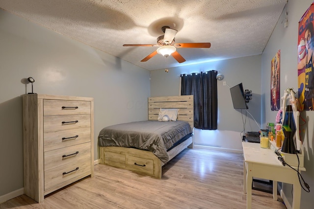 bedroom featuring light wood-style flooring, a textured ceiling, baseboards, and a ceiling fan