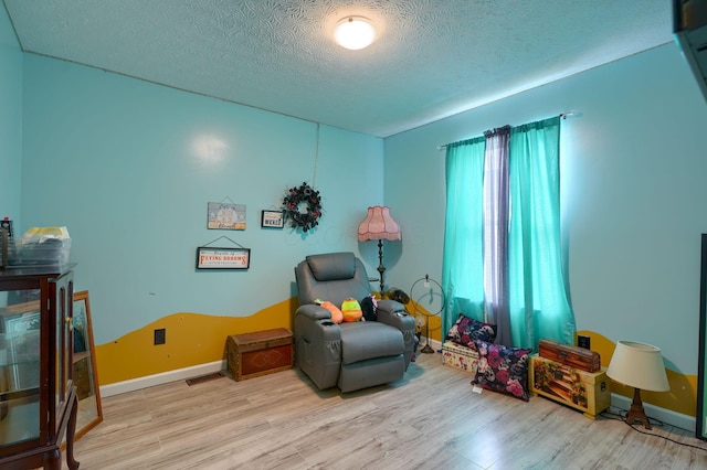 living area with baseboards, plenty of natural light, a textured ceiling, and wood finished floors