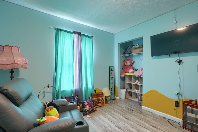 living area featuring light wood finished floors, a healthy amount of sunlight, a textured ceiling, and baseboards