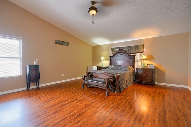 bedroom with a textured ceiling, wood finished floors, baseboards, and vaulted ceiling