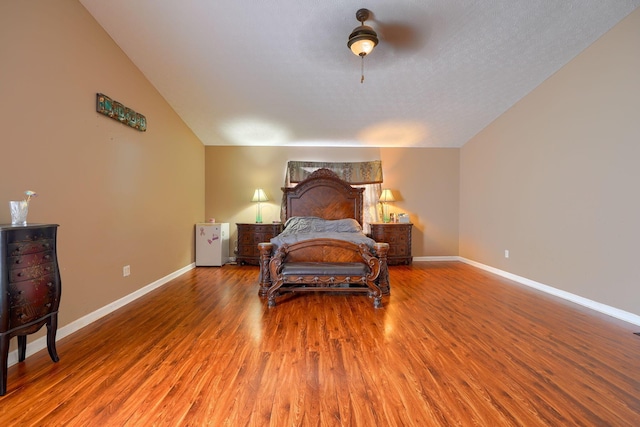 bedroom with vaulted ceiling, baseboards, and wood finished floors