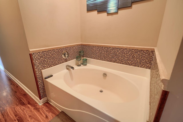 full bathroom with baseboards, a garden tub, and wood finished floors