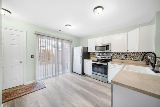 kitchen featuring a sink, stainless steel appliances, tasteful backsplash, and white cabinetry