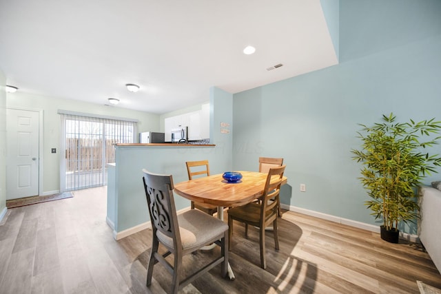 dining space with visible vents, light wood-style flooring, and baseboards